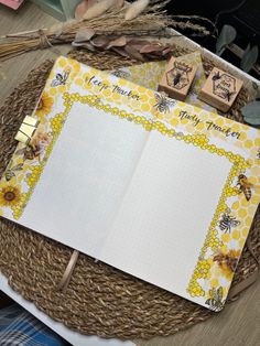 an open notebook sitting on top of a wicker basket next to some rubber stamps