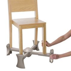 a child's wooden chair being held up by a person with their hand on the seat