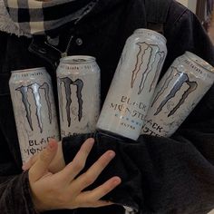 the man is holding six cans of monster energy drink in his hands and wearing a scarf