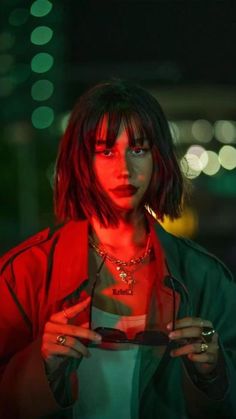 a woman with red hair and piercings holding a cell phone in her hands at night