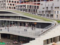 an aerial view of people walking and playing on the walkway in front of some buildings