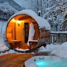 a hot tub sitting next to a wooden deck covered in snow