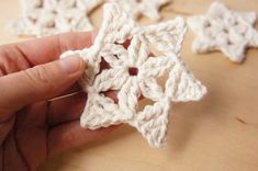 crocheted snowflakes are being held by someone's hand