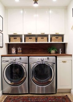 a washer and dryer in a small laundry room with white cabinets, rugs and baskets on the wall