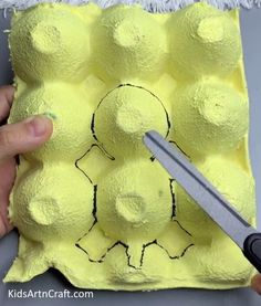 someone is cutting out an egg carton with scissors