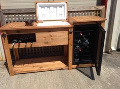 a wooden table with an ice chest on it's side and two wine glasses in the drawer