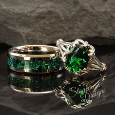 two rings with green and gold in them sitting on top of a black stone surface