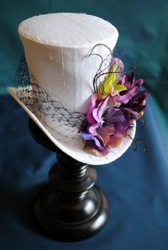 White Fascinator For Kentucky Derby Gift, White Mini Hats For Royal Ascot, Elegant White Costume Hat As Gift, Whimsical White Mini Hat For Gifts, Whimsical White Mini Hat As Gift, White Mini Hat With Handmade Flowers, White High Crown Mini Hat For Races, Whimsical White Mini Hat For Garden Party, White High Crown Top Hat For Races