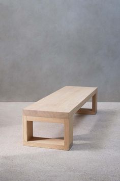 a wooden bench sitting on top of a white carpeted floor next to a gray wall