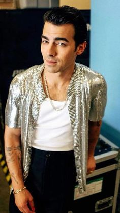 a man in a silver jacket standing next to a record player