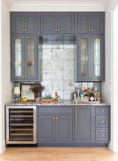 a kitchen with gray cabinets and silver counter tops, wine glasses on the top shelf