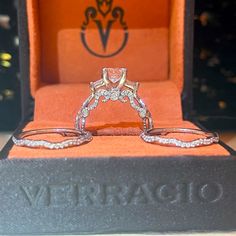 two wedding rings sitting on top of an orange velvet box with the word veraraq written below it