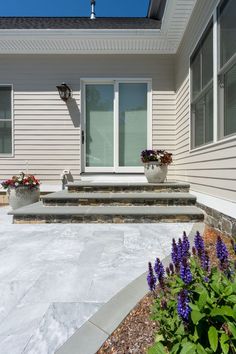 an outside view of a house with flowers in the foreground and steps leading up to the front door