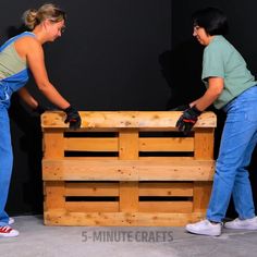 two women working on a wooden bench made out of pallet boards and wood crates