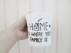 a hand holding up a coffee cup that says home is where you're family is