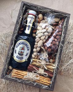 a bottle of beer sitting in a box filled with nuts and pretzel sticks