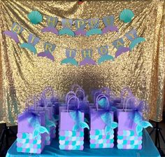 purple and blue gift bags are sitting on a table