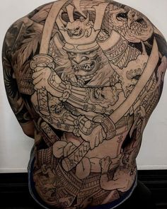 the back of a man's body with many tattoos on his chest and arms