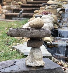 rocks stacked on top of each other in front of a small waterfall with water running down it