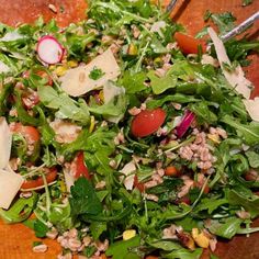 a close up of a salad on a cutting board with some utensils in it