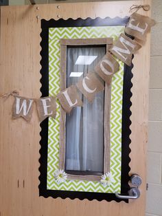 a welcome sign hanging from the side of a wooden door with burlocks and ribbon