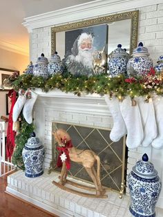 a fireplace decorated for christmas with blue and white ornaments, stockings, santa's stocking