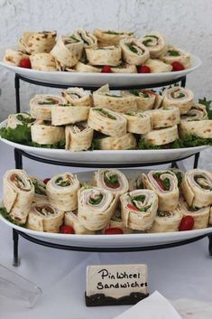 three tiered trays filled with sandwiches on top of a table next to a sign