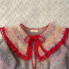 a knitted sweater with red lace on the collar