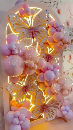 a pink and white butterfly light up display with balloons in the shape of butterflies on it