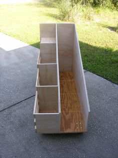 a wooden bench with drawers sitting on the side of a sidewalk in front of some grass