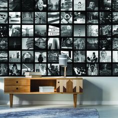 black and white photo collage on wall in living room with wooden table, lamp and dresser