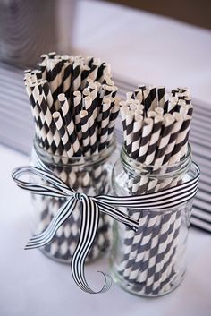 several black and white striped straws in a mason jar with ribbon on the side