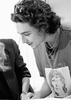 a man and woman are looking at something on a table with a book in front of them