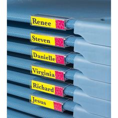 a stack of blue and yellow binders with name labels on them, in front of a white background