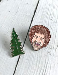 a pin with a christmas tree and a man's face on it, sitting next to a wooden background