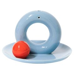 a blue and orange object sitting on top of a white plate next to an orange ball