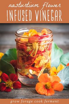 a jar filled with flowers sitting on top of a wooden table next to leaves and flowers