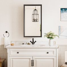 a bathroom with a sink, mirror and pictures hanging on the wall above it's counter