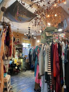 a room filled with lots of clothes hanging from the ceiling and lights on the ceiling