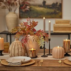 the table is set with candles, plates and vases for fall dinner party decor