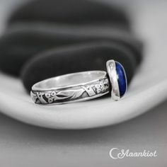 This striking Blue Sapphire Ring features a 10 mm x 8 mm oval cabochon of lab grown Blue Sapphire that has been securely set in a fine silver bezel. Traditionally, people attributed to Blue Sapphire the power to bring harmony between lovers as well as peace between adversaries. We are happy to create this beautiful ring for you in a variety of ring sizes, finish options, or in any of the stone choices shown in the images above. The band of this Sterling Silver ring features an Art Deco inspired Oval Lapis Lazuli Ring For Anniversary, Blue Oval Stackable Rings As Gift, Blue Oval Stackable Rings For Gift, Adjustable Oval Sapphire Birthstone Ring, Adjustable Oval Sapphire Ring As Birthstone, Oval Cabochon Stackable Jewelry As A Gift, Oval Cabochon Stackable Jewelry For Gifts, Oval Cabochon Stackable Jewelry Gift, Oval Lapis Lazuli Rings For Gift