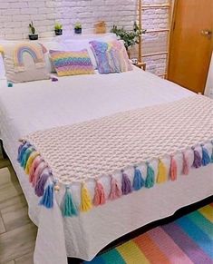 a white bed topped with a rainbow blanket and pillows