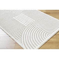 a white rug with wavy lines on the floor in front of a wooden flooring area