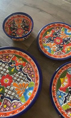 four colorful plates sitting on top of a wooden table