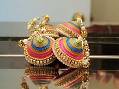 two pairs of colorful earrings sitting on top of a glass table next to a mirror