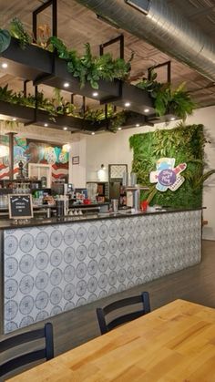 the inside of a restaurant with tables, chairs and plants hanging from the ceiling over the counter