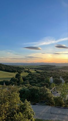 an aerial view of the countryside and trees at sunset, with some clouds in the sky