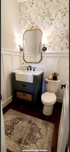 a white toilet sitting next to a sink in a bathroom on top of a wooden floor