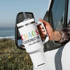 a person is holding a coffee cup in their hand while driving a truck by the beach