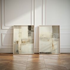 two framed paintings on the wall in an empty room with wood flooring and white walls